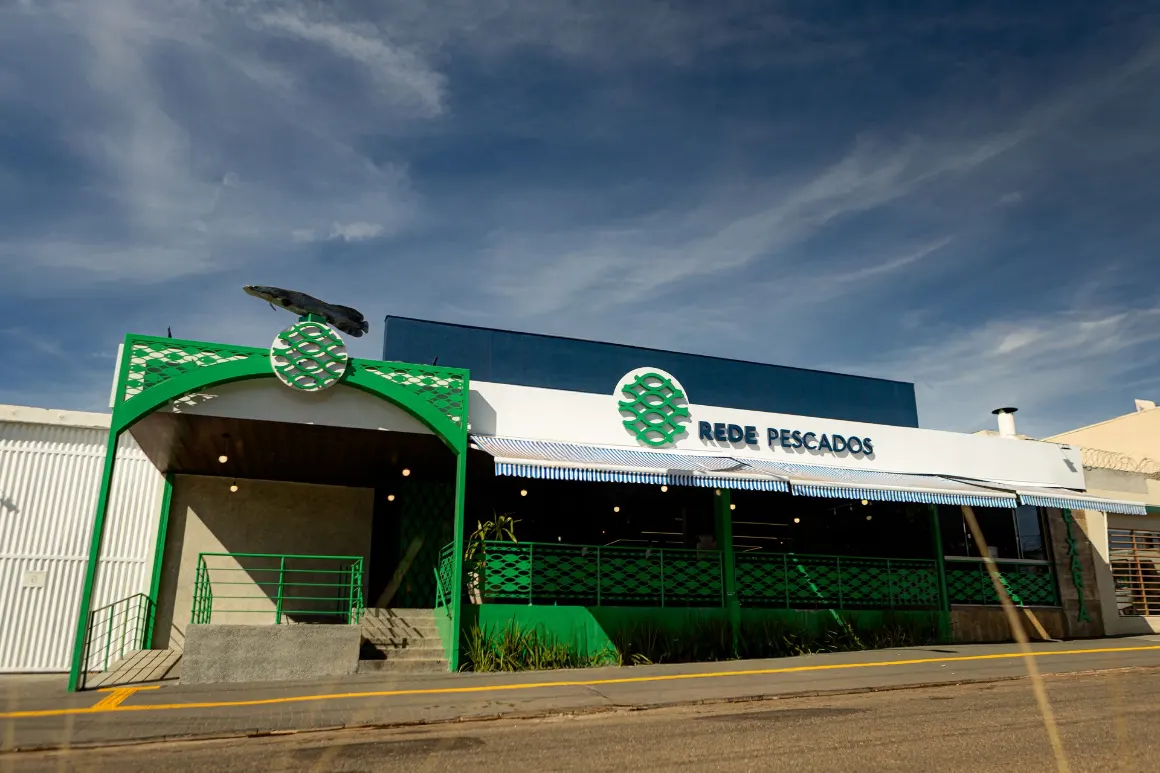 Fachada da Rede Pescados: toldo listrado, pilares verdes e placa azul-marinho