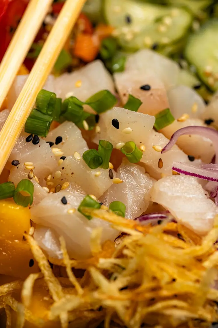 Cubos de peixe cru com manga, cebola roxa e batata palha